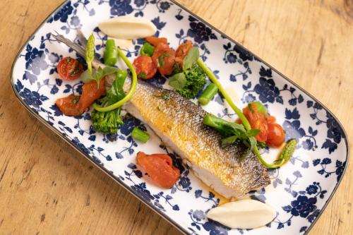 a plate of fish and vegetables on a table at Small Luxury Hotel Goldgasse in Salzburg
