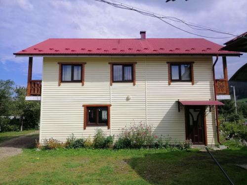 une petite maison blanche avec un toit rouge dans l'établissement Файна хата, à Verkhovyna