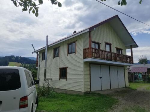 una furgoneta blanca estacionada frente a una casa en Файна хата, en Verkhovyna