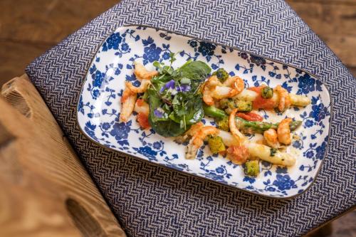 a plate of food with shrimp and greens on a table at Small Luxury Hotel Goldgasse in Salzburg