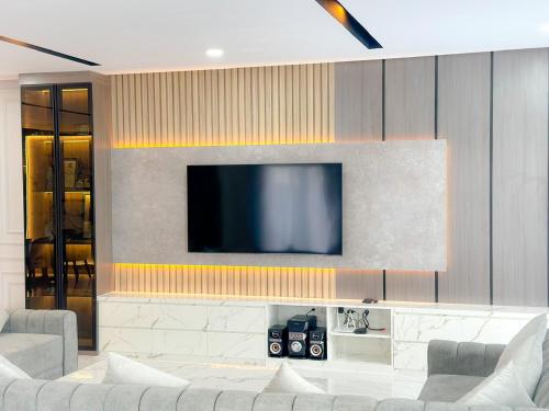 a living room with a television on a wall at Villa London Puncak in Sampal 2