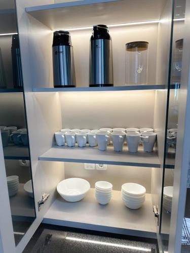 a shelf with white bowls and cups on it at Villa London Puncak in Sampal 2