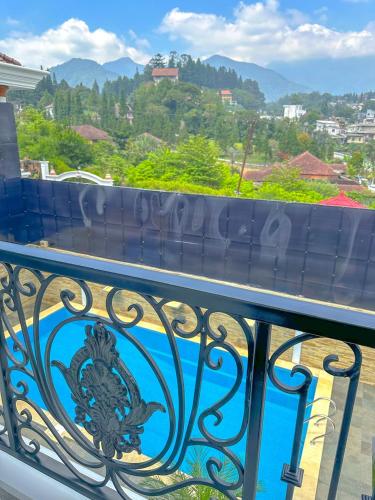 a balcony with a blue railing with mountains in the background at Villa London Puncak in Sampal 2