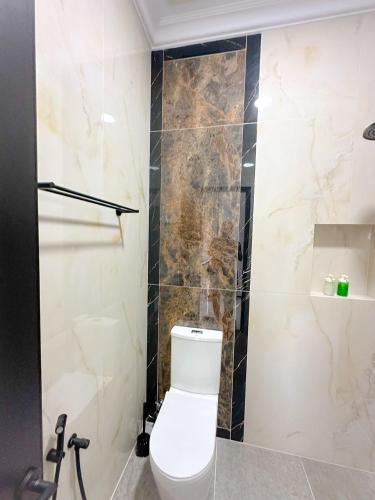 a bathroom with a toilet and a tiled wall at Villa London Puncak in Sampal 2