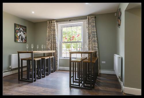 a room with a bar with stools and a window at Stubbs House, Loddon, sleeps 20, 2 hot tubs in Loddon