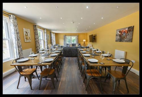 uma grande sala de jantar com uma mesa longa e cadeiras em Stubbs House, Loddon, sleeps 20, 2 hot tubs em Loddon
