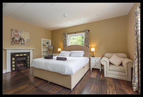 a bedroom with a bed and a chair and a fireplace at Stubbs House, Loddon, sleeps 20, 2 hot tubs in Loddon