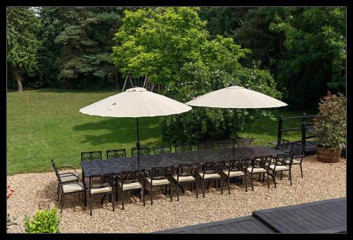 a black table and chairs with two umbrellas at Stubbs House, Loddon, sleeps 20, 2 hot tubs in Loddon