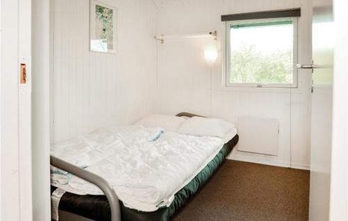 ブラーバンドにあるAmazing Home In Blvand With 4 Bedrooms, Sauna And Wifiのベッドと窓が備わる小さな白い客室です。