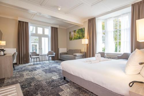 エールベークにあるFletcher Hotel Landgoed Huis te Eerbeekの白い大型ベッドと窓が備わるホテルルームです。
