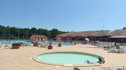 une grande piscine avec des personnes assises dans l'établissement Villa duplex Soustons plage,, à Soustons