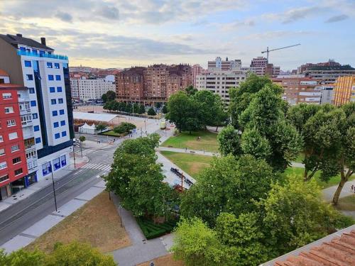 una ciudad con un parque con árboles y edificios en En el Parque de las Meanas., en Avilés