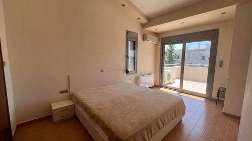 a bedroom with a bed and a large window at Daphne di Palio in Paleo Tsifliki