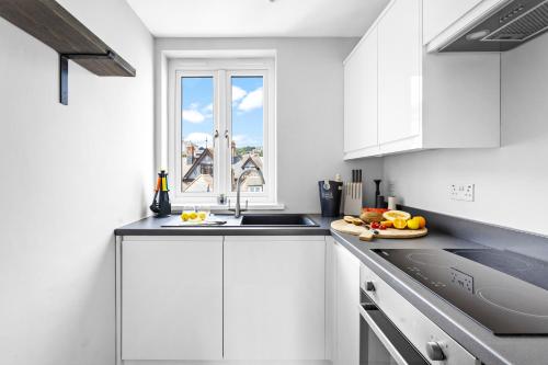 a kitchen with white cabinets and a sink and a window at Harbourside 3 - Luxury Riverside Apartment in Dartmouth