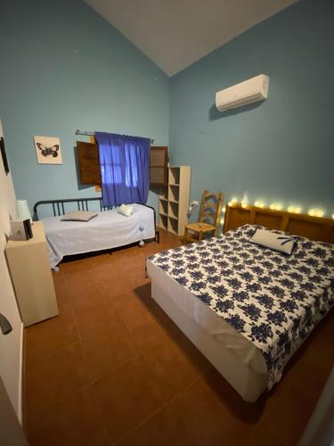 a bedroom with two beds and a blue wall at Casa Rural Los Almendros in Málaga