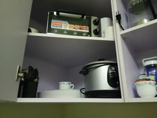 a kitchen cabinet with a slow cooker and other kitchen items at Avida Davao by davaobnb & Lemonique Homes in Davao City