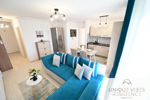 a living room with a blue couch and a kitchen at FLH - Unique Vibes Residence Magnolia Sibiu in Sibiu