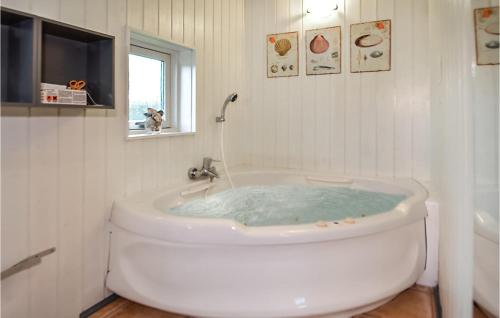 Baño blanco con bañera con un perro mirando por la ventana en Nice Home In Blvand With Sauna, en Blåvand