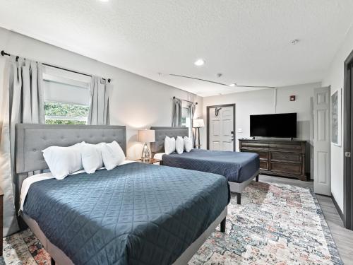 オカラにあるOcala Suitesのベッド2台、薄型テレビが備わるホテルルームです。
