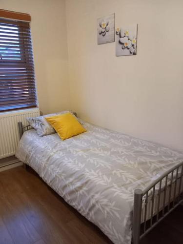 a bed in a bedroom with a yellow pillow on it at Beautiful Apartment in Hackney in London