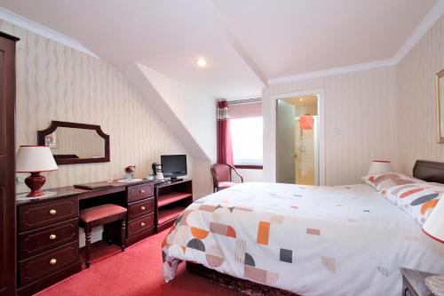 a bedroom with a bed and a desk and a mirror at The Jays Guest House in Aberdeen