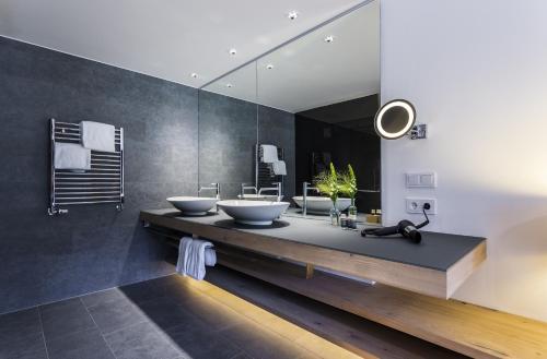 a bathroom with two sinks and a large mirror at Das Graseck - mountain hideaway & health care in Garmisch-Partenkirchen