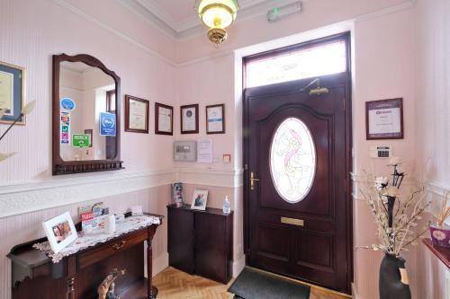 a room with a wooden door and a mirror at The Jays Guest House in Aberdeen