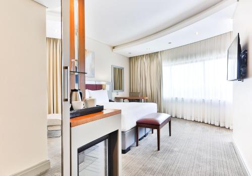 um quarto de hotel com uma cama e uma televisão em Holiday Inn Johannesburg-Rosebank, an IHG Hotel em Joanesburgo