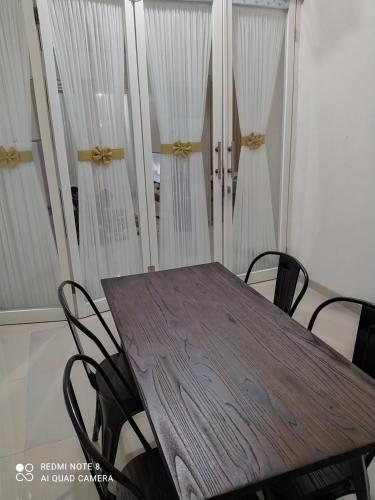 a wooden table and chairs in a room with curtains at Villa Permata Garden Blok D11 Near JTP 3 in Batu