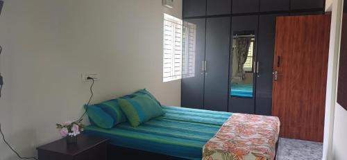 a bedroom with a bed with blue sheets and a door at SHI's Peaceful Oasis near Isha Adiyogi, Kovai Kuttralam Waterfalls & Karunya University in Alāndurai