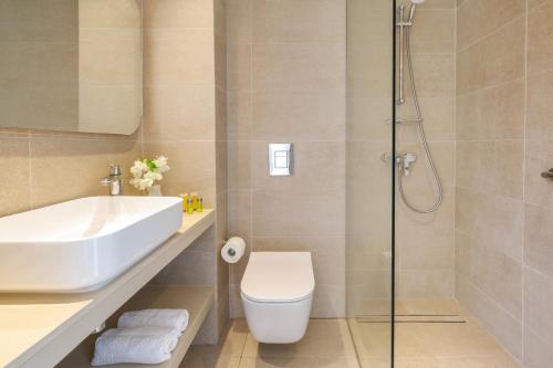uma casa de banho com um lavatório, um WC e um chuveiro em Nissi Park Hotel em Agia Napa