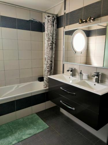 a bathroom with a sink and a tub and a mirror at Maison au calme chez Djé et Lucie in La Chapelle-dʼAligné