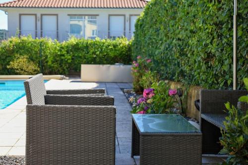 eine Terrasse mit Korbstühlen, einem Tisch und einem Pool in der Unterkunft Komplette Luxuriöse Villa mit fantastischer Aussicht 1000 qm Garten 10 min nach Saarbrücken in Oeting