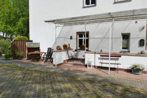 eine Terrasse mit Stühlen und einem Tisch neben einem weißen Haus in der Unterkunft Ferienwohnungen Fiedler in Neuhof