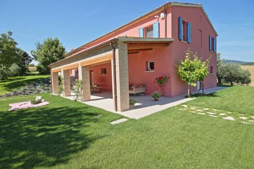 a pink house with a lawn in front of it at Villa del Cucco in Fossombrone