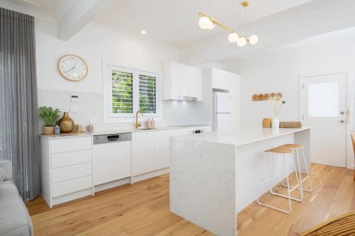 a white kitchen with white cabinets and a counter at Blissful Merewether Beach Cottage - A Coastal Gem in Newcastle