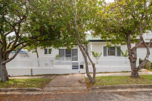 a white house with trees in front of it at Blissful Merewether Beach Cottage - A Coastal Gem in Newcastle