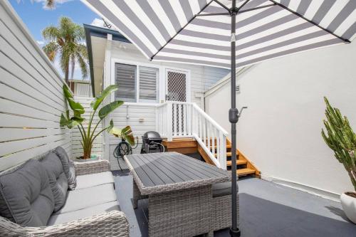 a patio with a table and an umbrella at Blissful Merewether Beach Cottage - A Coastal Gem in Newcastle
