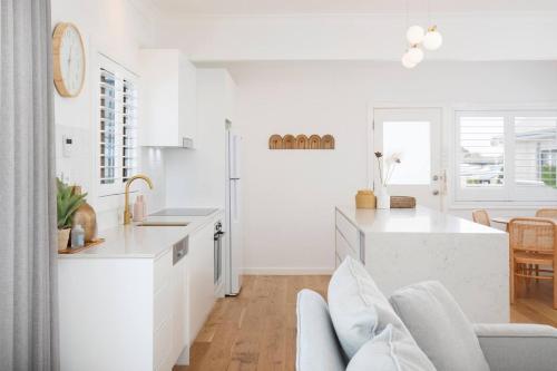 a kitchen with white cabinets and a white counter top at Blissful Merewether Beach Cottage - A Coastal Gem in Newcastle