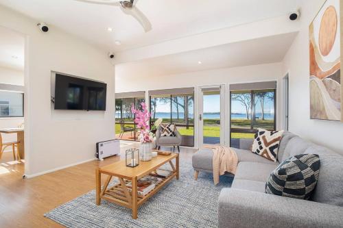 a living room with a couch and a table at 'Swan Cottage' Port Stephens Waterfront Solace in Newcastle