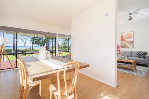 a dining room with a table and chairs and a couch at 'Swan Cottage' Port Stephens Waterfront Solace in Newcastle