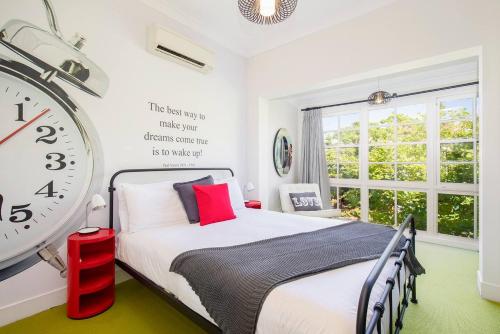 1 dormitorio con 1 cama y reloj grande en la pared en Times Square Terrace - Vibrant Charm in Newy's Heart en Newcastle