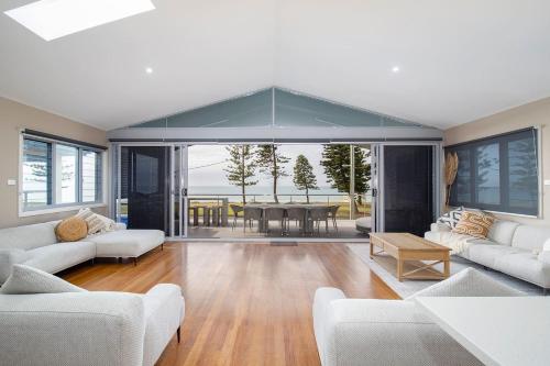 a living room with white couches and a table at 'Stockton Grande' A Sublime Beachfront Family Oasis in Newcastle