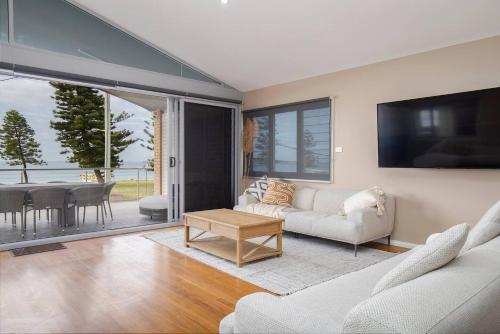 a living room with a couch and a table at 'Stockton Grande' A Sublime Beachfront Family Oasis in Newcastle