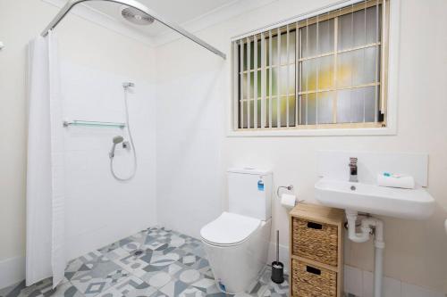 uma casa de banho branca com um lavatório e um WC em Tighes Hill Hideaway - Alfresco Living by the Park em Newcastle