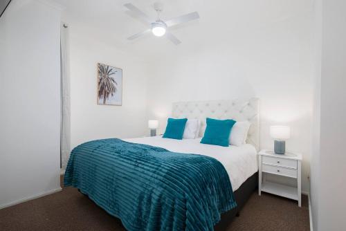 a white bedroom with a bed with blue pillows at 'Sandy Shores' A Spacious Newcastle Beach Escape in Newcastle