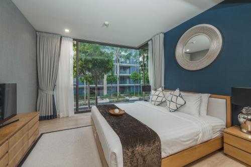 um quarto com uma cama grande e uma janela grande em Baan Mai Khao apartments Phuket em Praia de Mai Khao