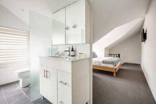 a bathroom with a sink and a toilet and a bed at Local's Corner - Boutique Living by Bondi Beach in Sydney