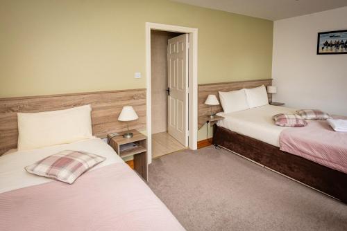 a hotel room with two beds and a doorway at Watersedge Seaviews in Kenmare