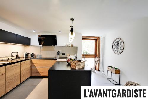 a kitchen with a black counter and a clock on the wall at L'AvantGardiste, Spacious 6 bedrooms duplex, panoramic view in Crans-Montana